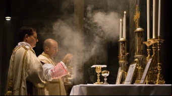 Un sacerdote católico celebra la Misa tradicional en latín con un diácono y subdiácono, incensando el altar en la Iglesia de San Pancracio, Roma.
