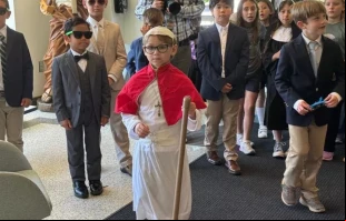 El joven "Papa David" saluda a los fieles por los pasillos de la Pinecrest Academy, acompañado de sus cardenales y su equipo de seguridad. Crédito: Pinecrest Academy.